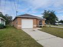 Tan one-story house with a white garage door at 590 E Lemon Ave, Lake Alfred, FL 33850