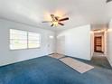 Living room featuring blue carpet, ceiling fan and access to hallway at 221 Dorothy St, Auburndale, FL 33823