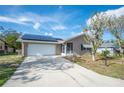 Front view of tan house with solar panels and a screened porch at 7035 Tamarind Dr, Lake Wales, FL 33898