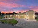 Evening view of a charming yellow house with a large driveway and three-car garage at 3604 Blackmoor Ln, Lake Wales, FL 33859
