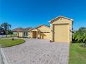 Front view of a charming yellow house with a large driveway and three-car garage at 3604 Blackmoor Ln, Lake Wales, FL 33859