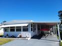 Front view of a white mobile home with carport and small yard at 161 Bonnie Dr, Auburndale, FL 33823