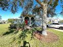 Gray house with red door, landscaping, and a car parked in the driveway at 4150 Bedford Ave, Winter Haven, FL 33884