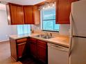 Compact kitchen featuring wood cabinets, double sink, and white appliances at 16 Kendra Ct # 16, Winter Haven, FL 33880