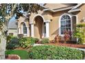 Tan house with arched entryway, white columns, and manicured landscaping at 231 Terranova Blvd, Winter Haven, FL 33884
