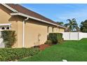 Landscaped side yard with tan house exterior, lush greenery, and white fence at 231 Terranova Blvd, Winter Haven, FL 33884