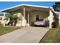 Mobile home with carport, landscaping, and driveway at 418 Village Sw Cir, Winter Haven, FL 33880