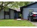 Gray house with a black car parked in the driveway, a well-maintained lawn, and mature trees at 1189 Rib Ave, Saint Cloud, FL 34771