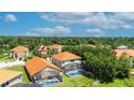 Aerial perspective of houses with orange roofs, pools, and a large green space at 390 Miro Dr, Davenport, FL 33837