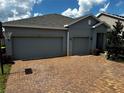 Two-story house with gray siding, two-car garage, and a brick driveway at 567 Blackstone St, Minneola, FL 34715