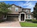Two-story house with a brown facade and brick driveway at 1402 Wexford Way, Davenport, FL 33896