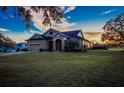 House exterior at sunset, showcasing landscaping and a two-car garage at 1004 Country Oaks Ln, Lakeland, FL 33810