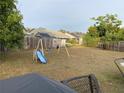 Large backyard with a swing set, grass, and a partial view of a fence at 2103 Pimlico St, Orlando, FL 32822