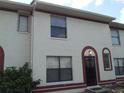 Townhome exterior featuring a light-colored facade, red trim, and a centered entrance at 6274 Whispering Way # 130, Orlando, FL 32807