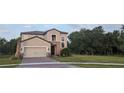 Two-story home with gray siding, brick accents and a three car garage at 3937 Reed Grass Pl, Kissimmee, FL 34746