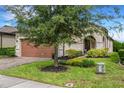 Beige house with brown garage door and landscaped yard at 793 Asturias Rd, Davenport, FL 33837