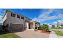 Two-story house with tan exterior, solar panels, and a brick driveway at 2585 Needlepoint St, Kissimmee, FL 34741