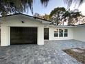 Updated home exterior boasts a modern black garage door and a gray paver driveway at 1204 Lake Elbert Se Dr, Winter Haven, FL 33880