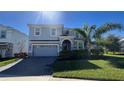 Two-story house with gray siding, a three-car garage, and manicured lawn at 8830 Interlocking Ct, Davenport, FL 33896