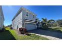 Side view of two-story house with gray siding, gray driveway, and landscaping at 8830 Interlocking Ct, Davenport, FL 33896