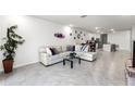 Open living room with light tile floors, large sectional sofa, and view into kitchen at 2928 Sunridge Loop, Saint Cloud, FL 34771