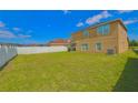 Large backyard with grassy lawn, a white fence, and a two-story house at 4907 Rockvale Dr, Kissimmee, FL 34758