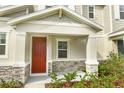 Covered front porch with stone accents and a red door at 1472 Erin Breeze Ln, Kissimmee, FL 34744