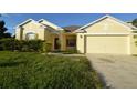 Yellow house with two-car garage and landscaped yard at 2221 The Oaks Blvd, Kissimmee, FL 34746
