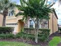 Two-story house with a yellow facade, brick driveway, and lush landscaping at 2131 Tripoli Ct, Kissimmee, FL 34747
