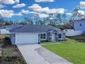 New gray house with white garage door, stone accents, and a well-maintained lawn at 16619 Sw 31St Cir, Ocala, FL 34473