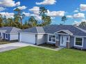 Brand new gray house with white garage door, stone accents, and a nicely landscaped yard at 16619 Sw 31St Cir, Ocala, FL 34473