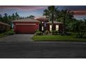 Red two-story house with paved driveway and landscaping at dusk at 806 Ebb Tide Ln, Poinciana, FL 34759