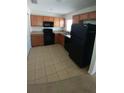 Kitchen with wood cabinets, black appliances, and tile floor at 2919 Puerta Del Sol Blvd, Kissimmee, FL 34744