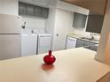 Kitchen features white appliances, gray cabinets, and a laundry closet at 414 Banana Cay Dr # I, South Daytona, FL 32119