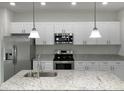 Modern kitchen featuring white cabinets, granite countertops, and stainless steel appliances at 274 Elm Ct, Kissimmee, FL 34759