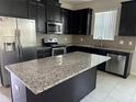 Modern kitchen with dark cabinets, granite island, and stainless steel appliances at 2757 Creekmore Ct, Kissimmee, FL 34746