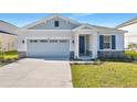 Curb appeal of a one-story house featuring gray siding, stone accents, and a two-car garage at 4043 Bannock Ave, Tavares, FL 32778