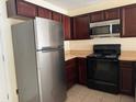 Kitchen with dark wood cabinets and stainless steel appliances at 624 Cresting Oak Cir # 32, Orlando, FL 32824