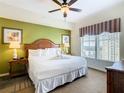 King-size bed in a well-lit bedroom with a green accent wall and a ceiling fan at 8125 Resort Village Dr # 51104, Orlando, FL 32821