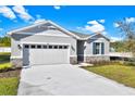 One-story home with gray siding, stone accents, and a two-car garage at 4063 Bannock Ave, Tavares, FL 32778