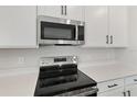 Stainless steel gas cooktop and microwave in a white kitchen at 4256 Sawtooth Ct, Tavares, FL 32778