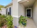 Inviting front entry with a covered porch, black front door, and potted plants at 2894 Mosshire Cir, Saint Cloud, FL 34772