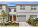 Modern townhouse exterior with gray siding, orange doors, and a two-car garage at 4801 Sparkling Shell Ave, Kissimmee, FL 34746