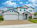 Two-story house with gray siding, three-car garage, and landscaped yard at 2867 Matera Dr, St Cloud, FL 34771