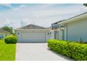 Attached garage with light gray door and paver driveway at 157 Bell Tower Xing E, Kissimmee, FL 34759