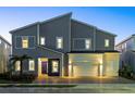 Modern two-story house with gray siding, two-car garage, and nighttime lighting at 1735 Oak Blossom Dr, Davenport, FL 33837
