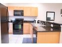 Galley kitchen with black appliances and granite countertops at 3006 Red Ginger Rd, Kissimmee, FL 34747