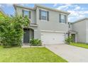 Two-story house with gray siding, white garage door, and landscaping at 6728 Huntleigh Hammock Rd, Harmony, FL 34773