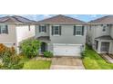 Two-story house with gray siding, white garage door, and landscaping at 6728 Huntleigh Hammock Rd, Harmony, FL 34773
