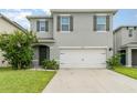 Two-story house with gray siding, white garage door, and landscaping at 6728 Huntleigh Hammock Rd, Harmony, FL 34773